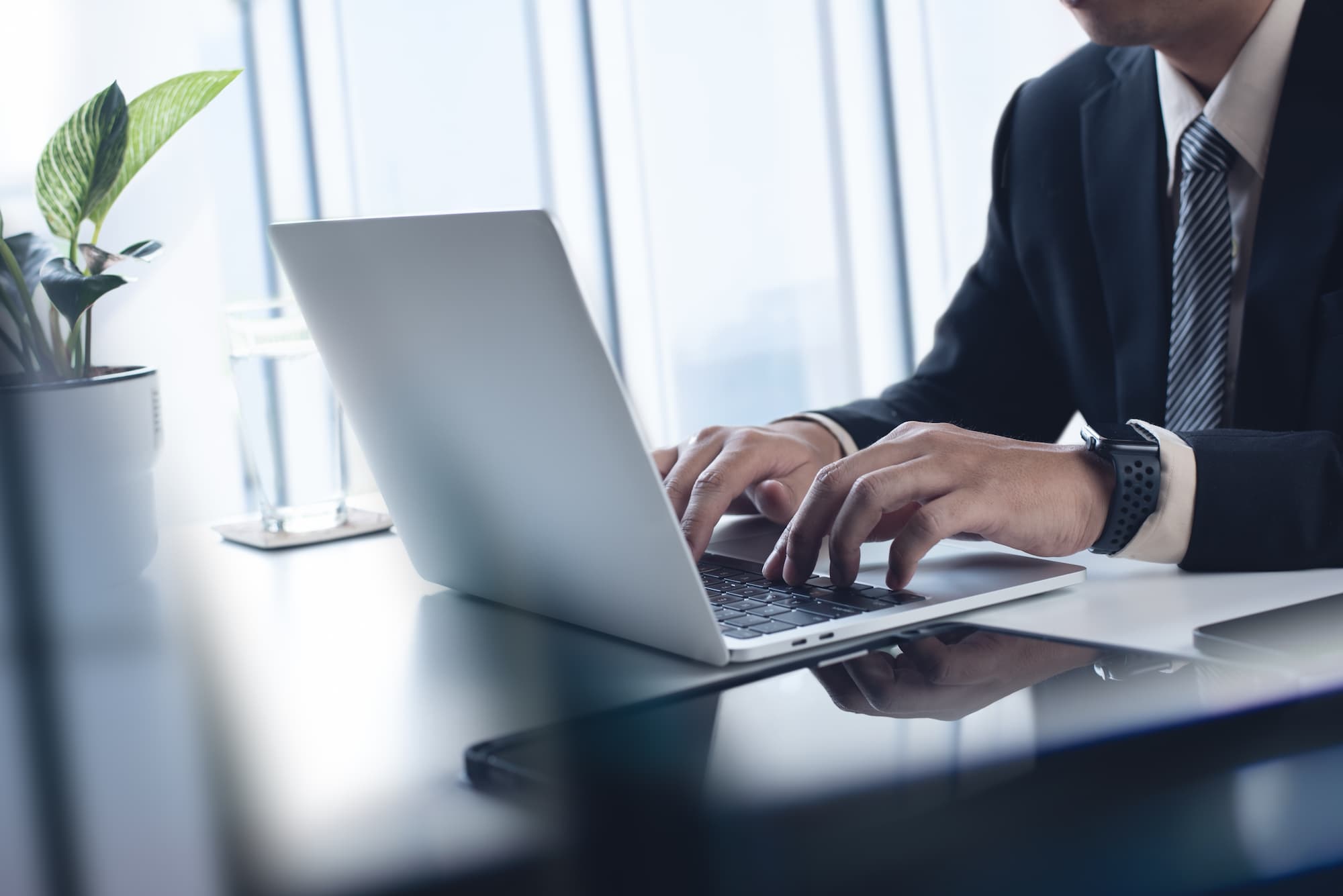 Un hombre en traje está tecleando en una laptop, mirando atentamente la pantalla, creando conexiones con peering.