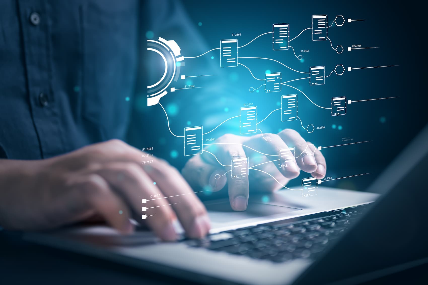 Una persona teclea en una laptop mientras observa una interfaz digital a través de pering.