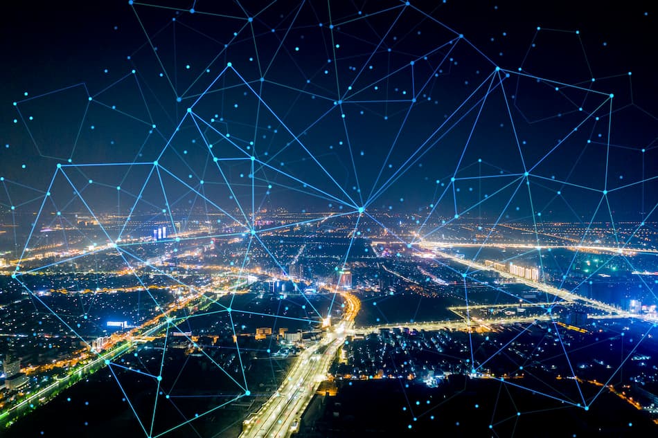La ciudad iluminada por líneas de red y puntos conectados, con Towering 5G destacándose en el horizonte.