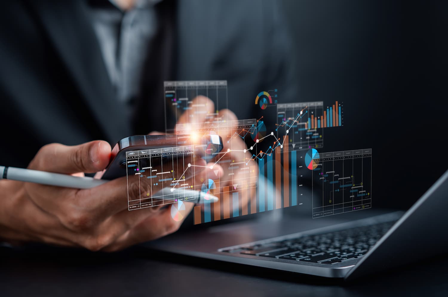 Hombre de negocios usando una laptop con gráficos y datos empresariales en la pantalla, conectado a internet.
