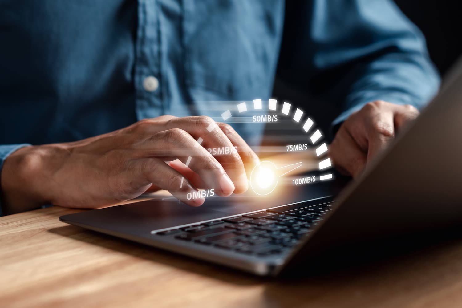 Una persona tecleando en una laptop con un velocímetro, simbolizando la velocidad de conexión a Internet.