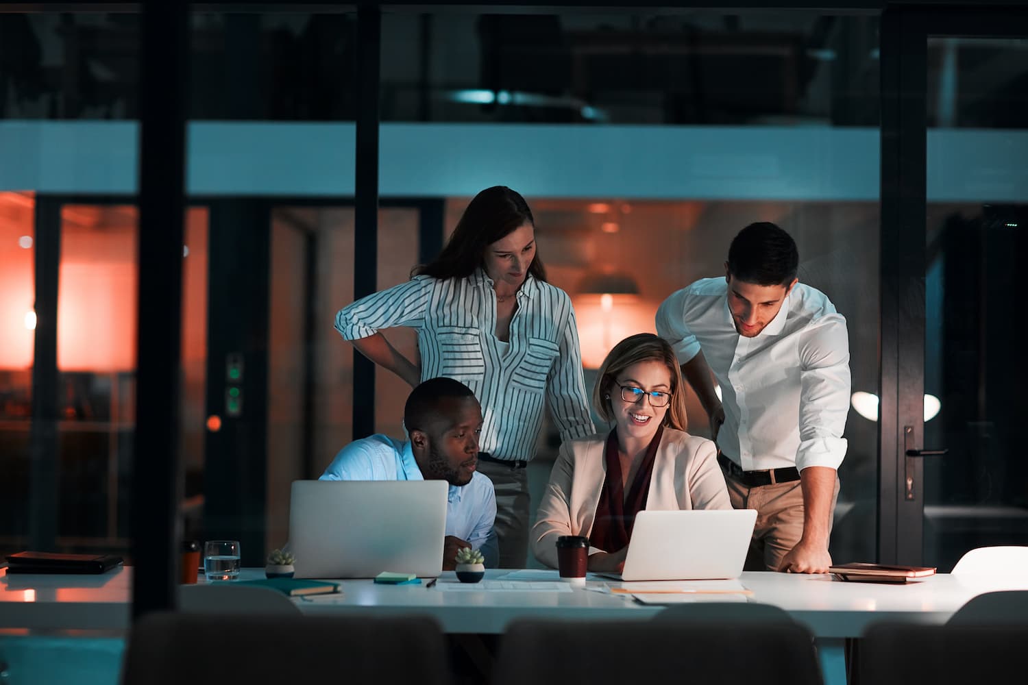 Un grupo de personas colaborando en un portátil en una oficina, utilizando Internet para trabajar en equipo.