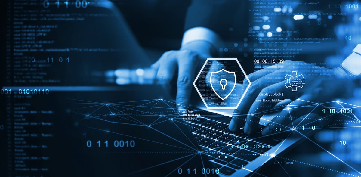 Una persona escribe en un portátil que tiene un escudo, simbolizando protección en internet.