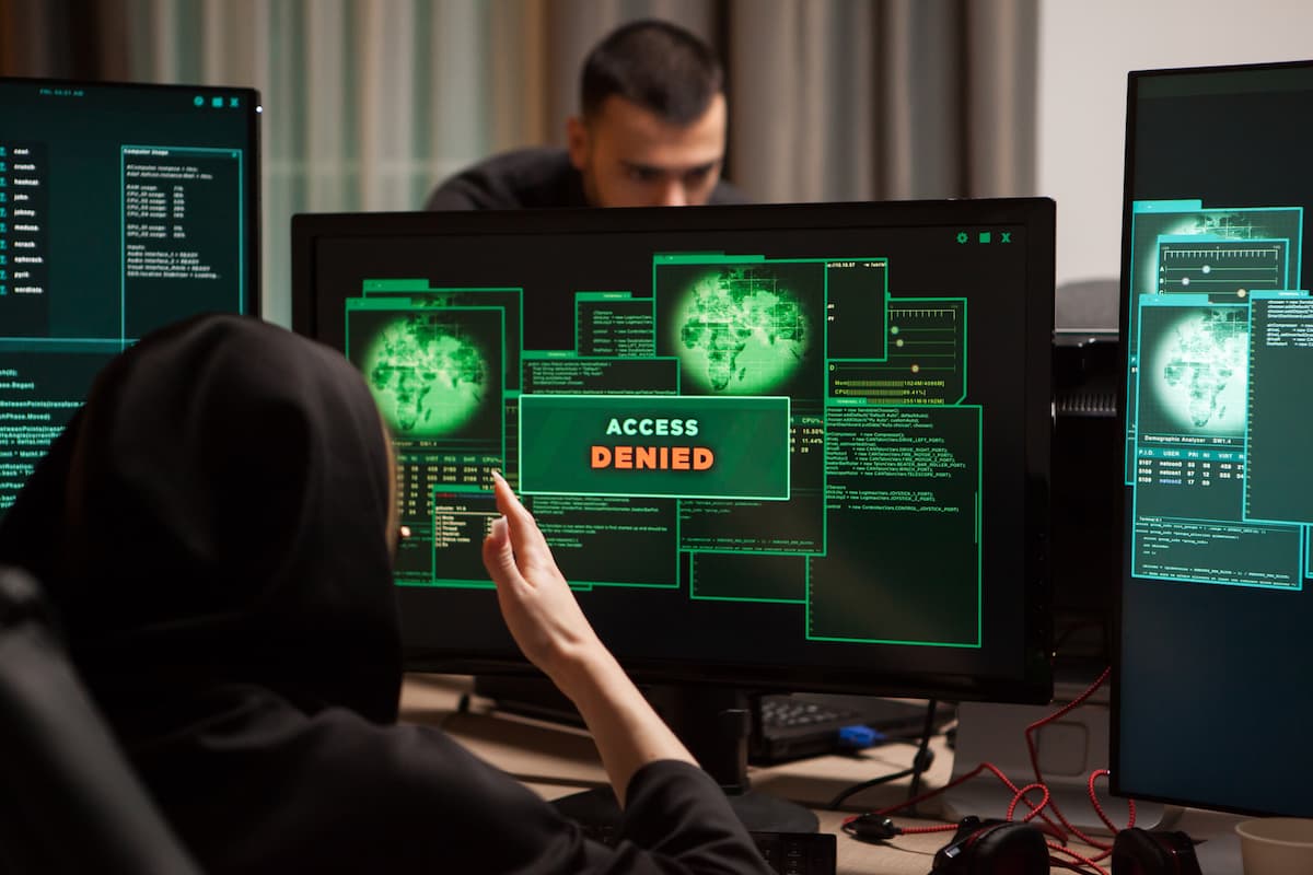 Hombre con sudadera observa una pantalla de computadora, posiblemente analizando datos sobre protección contra DDoS.