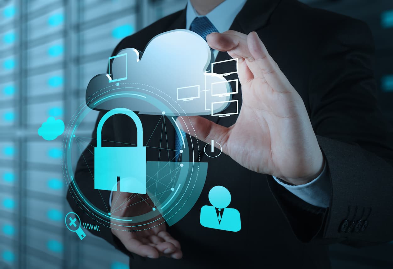 Empresario sostiene un candado y un ícono de nube frente a un servidor, simbolizando protección contra ataques DDoS.