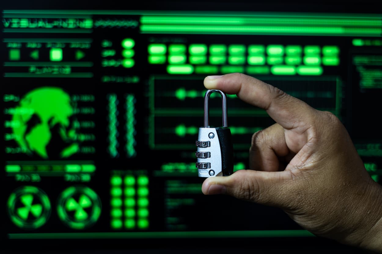 A person holds a small key in front of a computer screen, symbolizing security against phishing attacks.