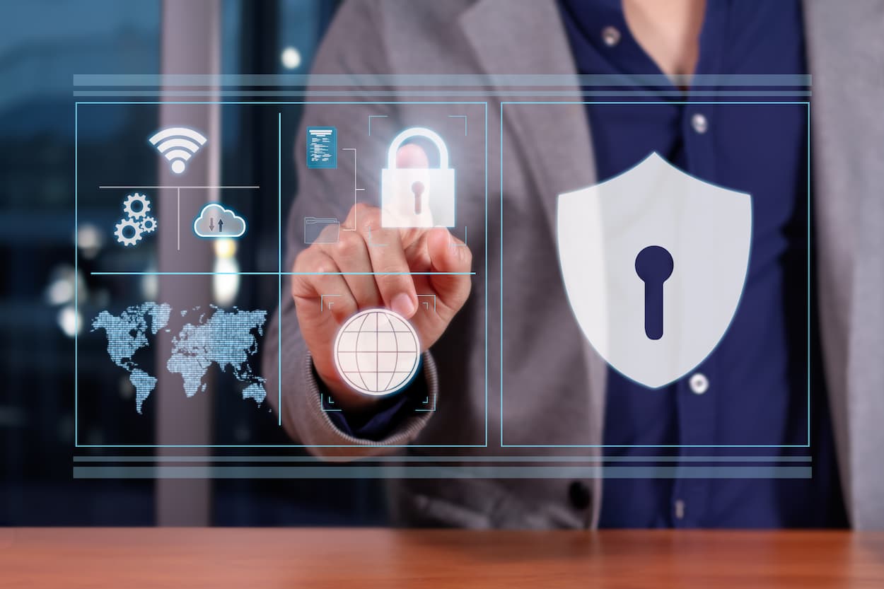 Empresario sosteniendo un ícono de seguridad virtual en la pantalla, simbolizando protección contra ataques DDoS.