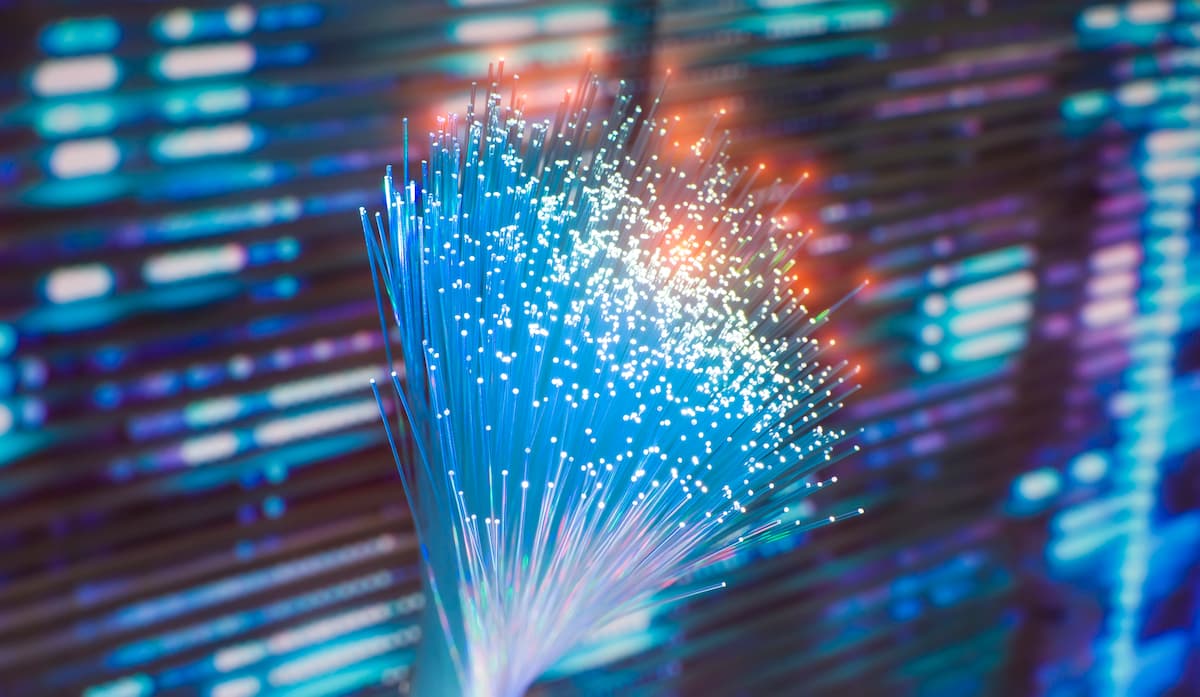 Cable de fibra óptica frente a una pantalla de computadora, simbolizando la protección contra ataques DDoS.