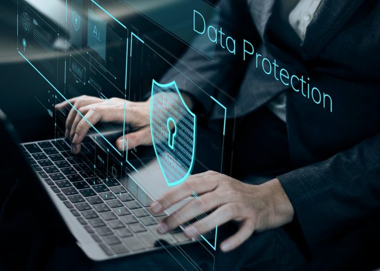 Persona en traje tecleando en un portátil con el texto "protección de datos" visible en la pantalla con Anti-DDos