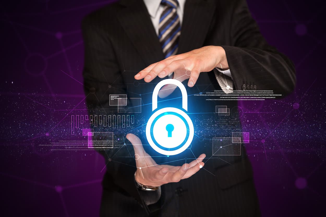 Empresario sostiene un candado con un ícono digital, simbolizando la protección contra ataques DDoS.